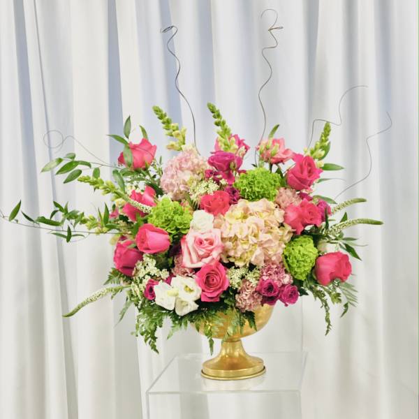 Pink and green floral arrangement in a gold pedestal vase
