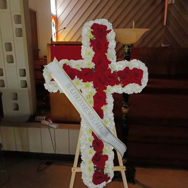 Cross-shaped floral tribute of red and white flowers on an easel