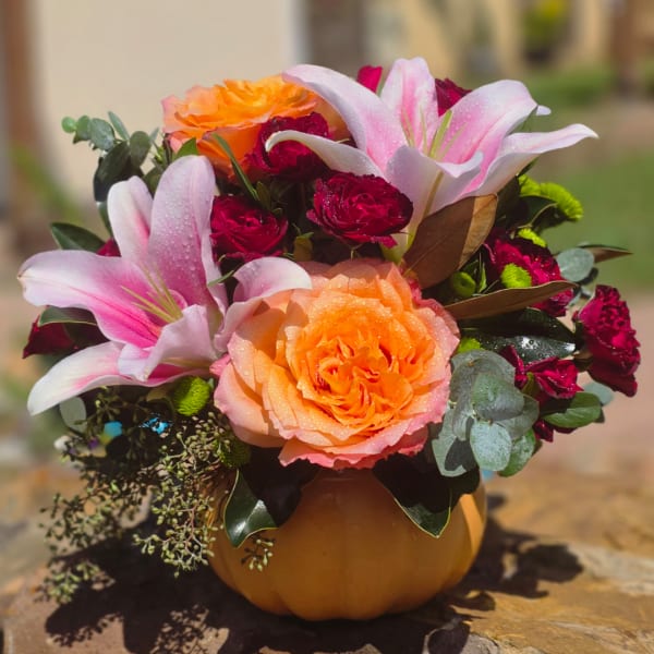 Pink lilies and orange roses in a pumpkin-shaped vase