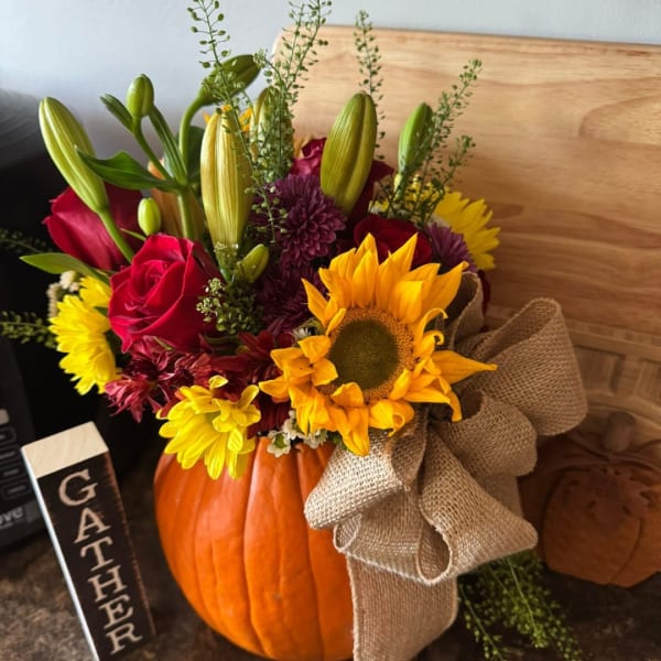 Fall floral arrangement in a pumpkin with sunflowers, roses, and lilies