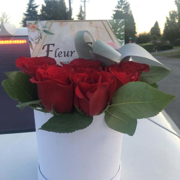 Red roses arranged in a white hat box with a ribbon