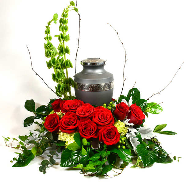 Red roses arranged around a gray urn with tall green accents