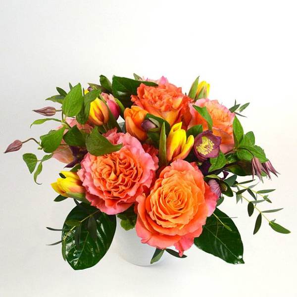 Orange and pink rose bouquet in a white vase