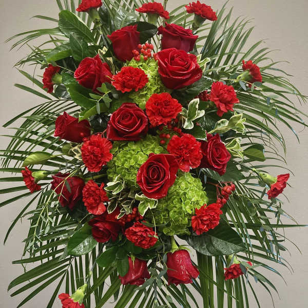 Standing floral spray with red roses and carnations on a tripod easel