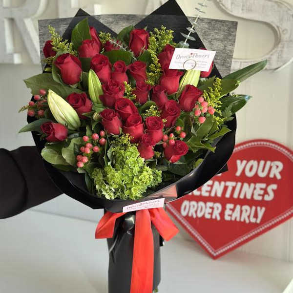 Bouquet of red roses with lilies and greenery wrapped in black paper