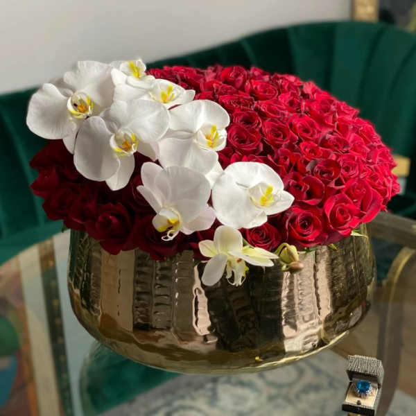 Red roses and white orchids arranged in a gold bowl.