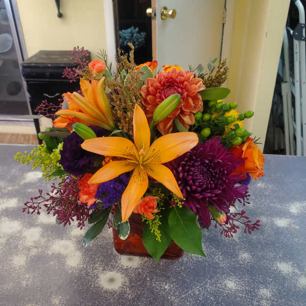 Orange lilies and purple chrysanthemums in a glass vase