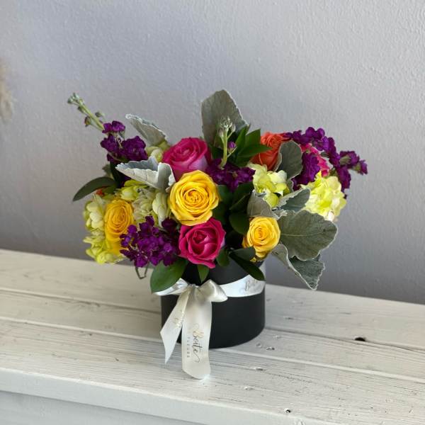 Colorful rose bouquet in a black hat box with a ribbon