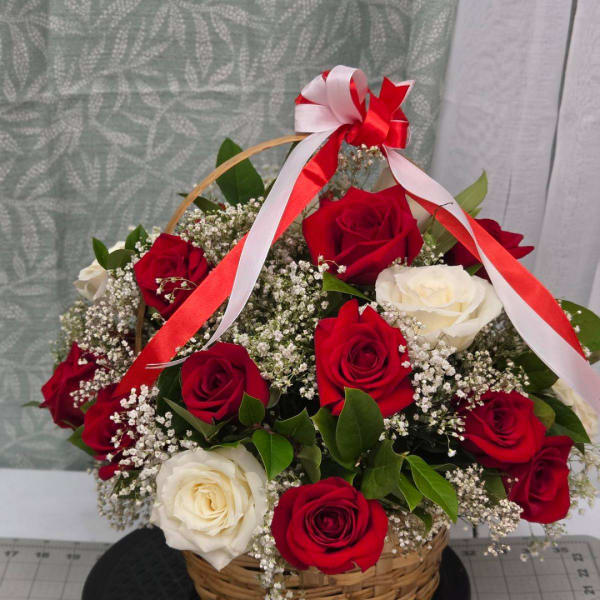 Basket arrangement of red and white roses with ribbon
