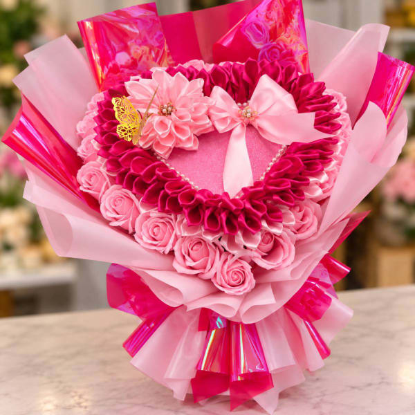 Pink heart-shaped bouquet with ribbon flowers and a butterfly accent