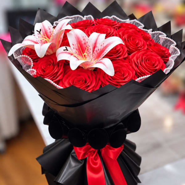 Bouquet of red roses with two white lilies in black wrap
