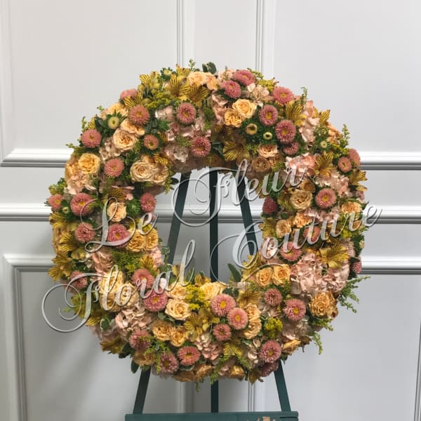 Large floral wreath on an easel with pink, peach, and yellow blooms