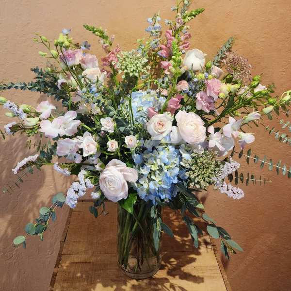 Pastel bouquet of roses, hydrangeas, and orchids in a glass vase
