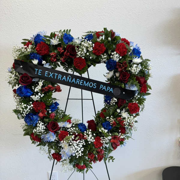 Heart-shaped floral wreath on an easel with a memorial ribbon