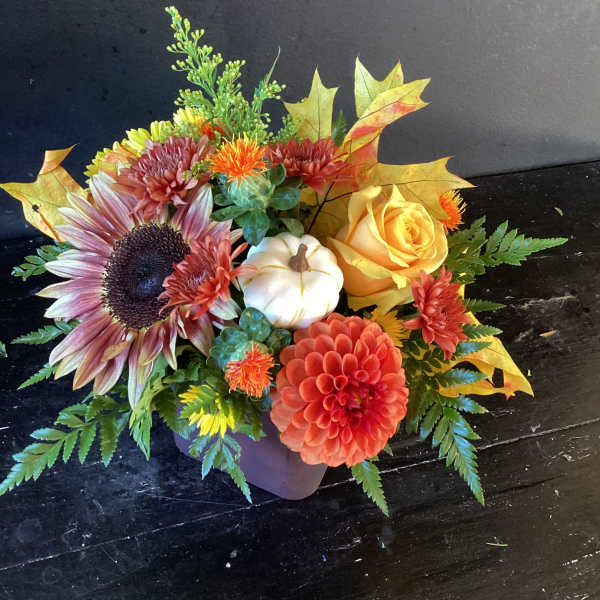 Autumn floral arrangement with a sunflower, yellow rose, and pumpkin accent in a vase