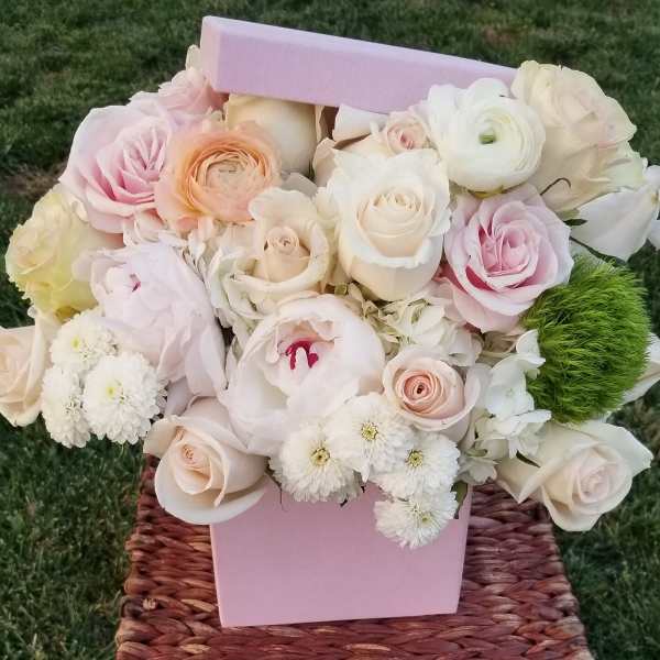 Pastel bouquet of roses and ranunculus in a pink box