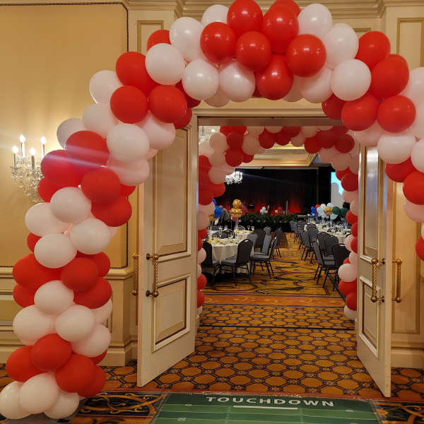 Red and white balloon arch framing open double doors