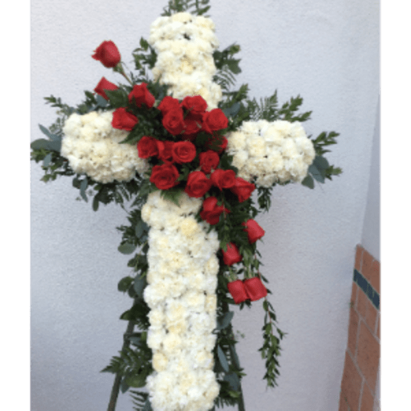 Floral cross made of white flowers with red roses and greenery