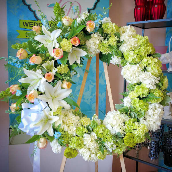Large floral wreath with white lilies, roses, and green hydrangeas on an easel