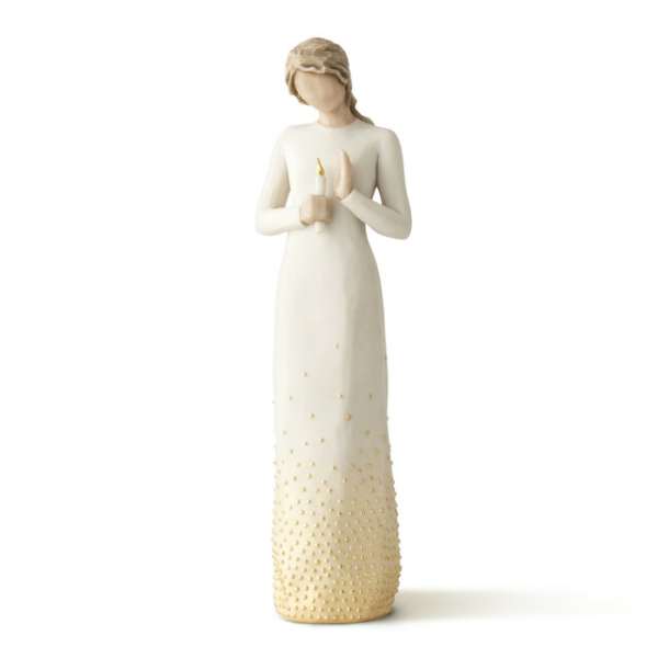 A figurine of a woman in a long cream dress holding a candle.