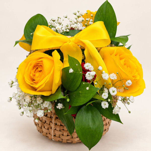 Yellow roses in a woven basket with a large yellow ribbon