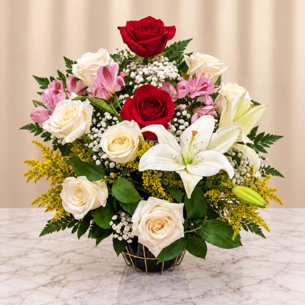 Bouquet of red and white roses with lilies in a black vase