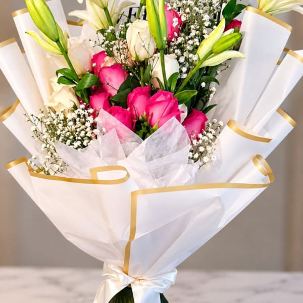 Bouquet of pink and white roses with lilies wrapped in white paper