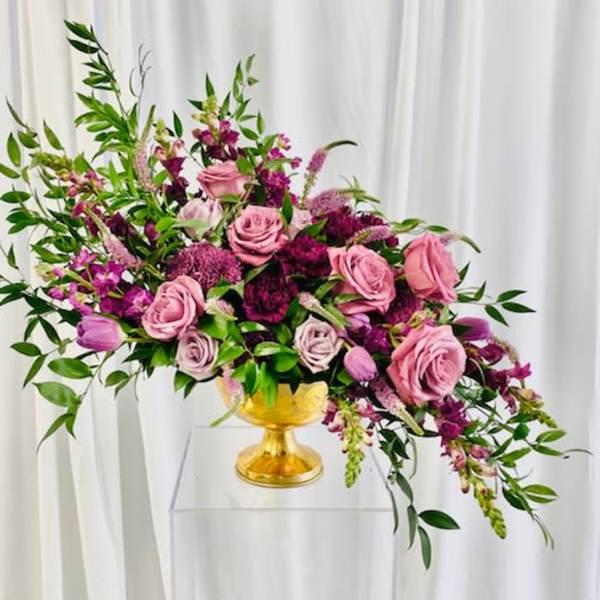 Pink and purple rose arrangement in a gold vase