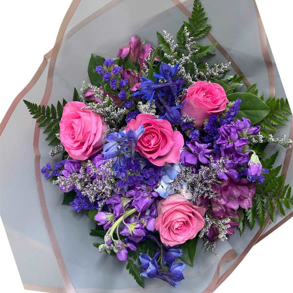 Bouquet of pink roses and purple flowers wrapped in translucent paper
