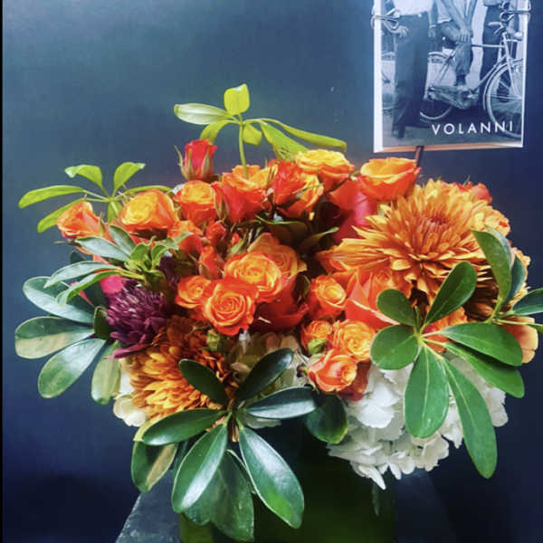 Orange roses and chrysanthemums arranged in a square glass vase