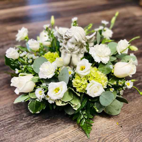 White floral arrangement with a small angel figurine in the center