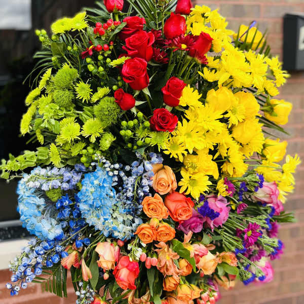 Large standing spray of multicolored flowers with red roses and yellow daisies