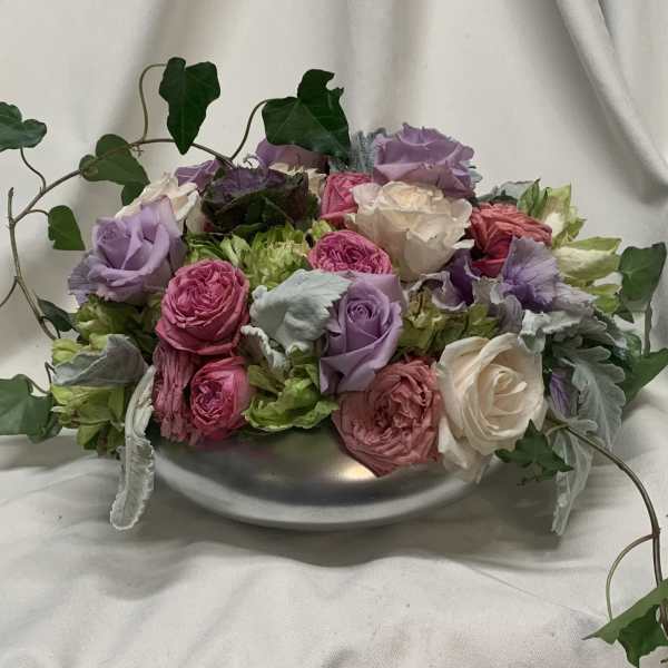 Mixed pink, lavender, and white roses in a low silver bowl