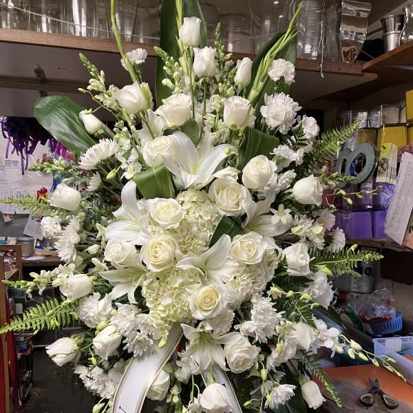 Large white funeral standing spray with roses and lilies