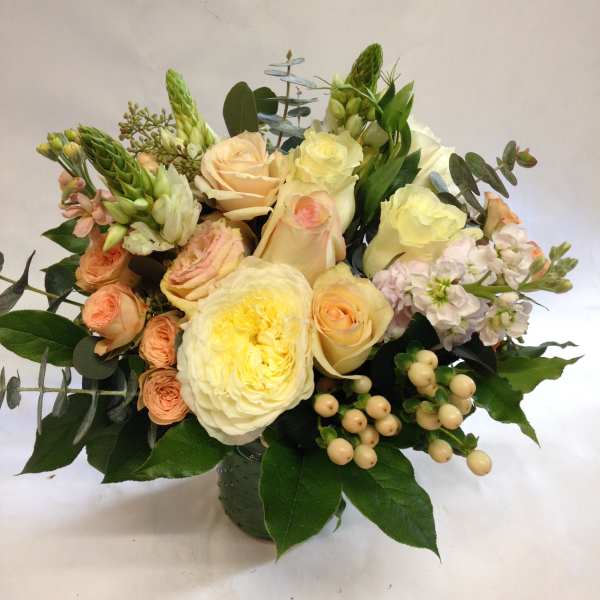 Bouquet of cream and peach roses with pale pink flowers in a vase