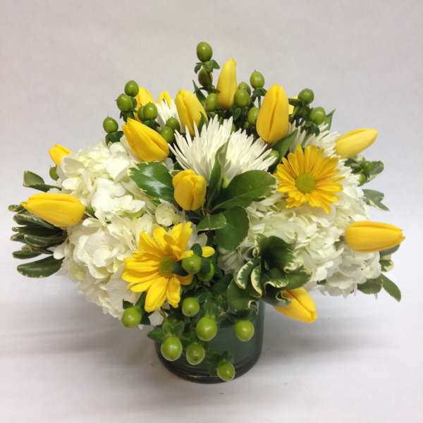 Yellow tulips and white flowers in a dark glass vase