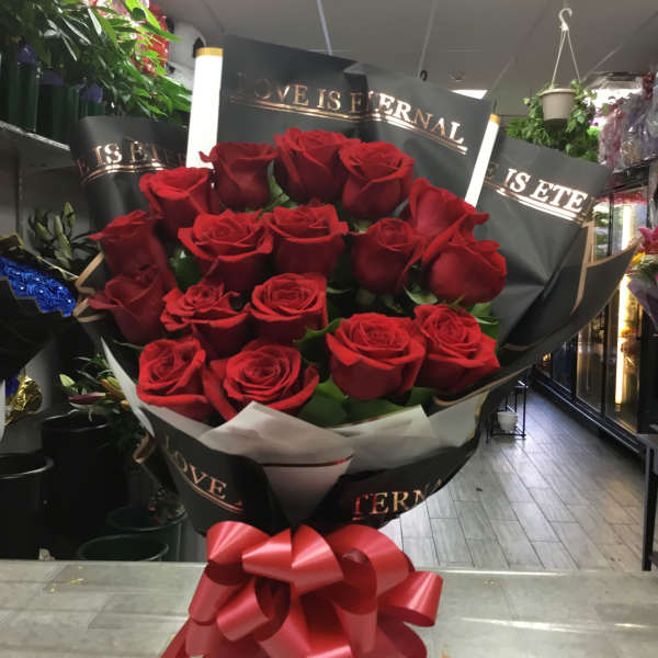 Bouquet of red roses wrapped in black paper with a red bow