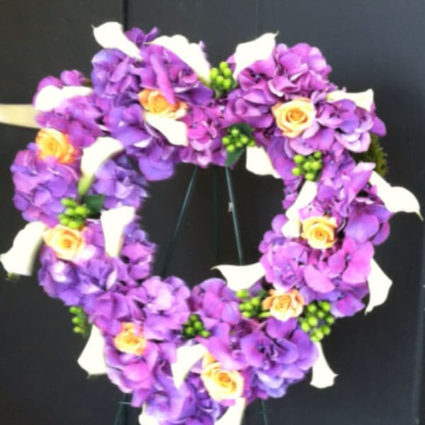 Heart-shaped floral wreath with purple flowers, white calla lilies, and yellow roses