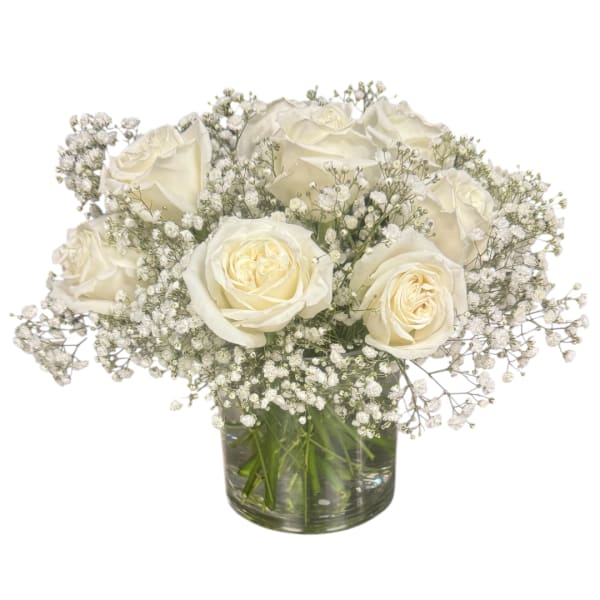 White roses and baby's breath arranged in a clear glass vase