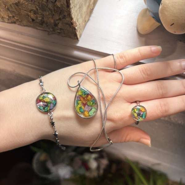 Hand wearing colorful resin jewelry with dried flowers