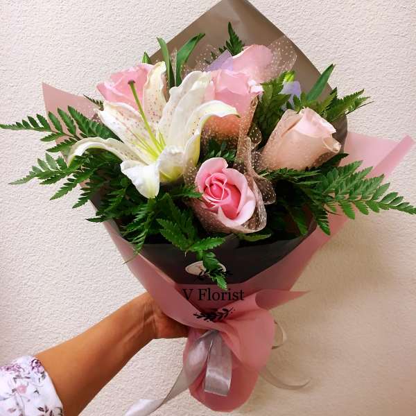 Pink roses and white lilies in pink and brown wrapping