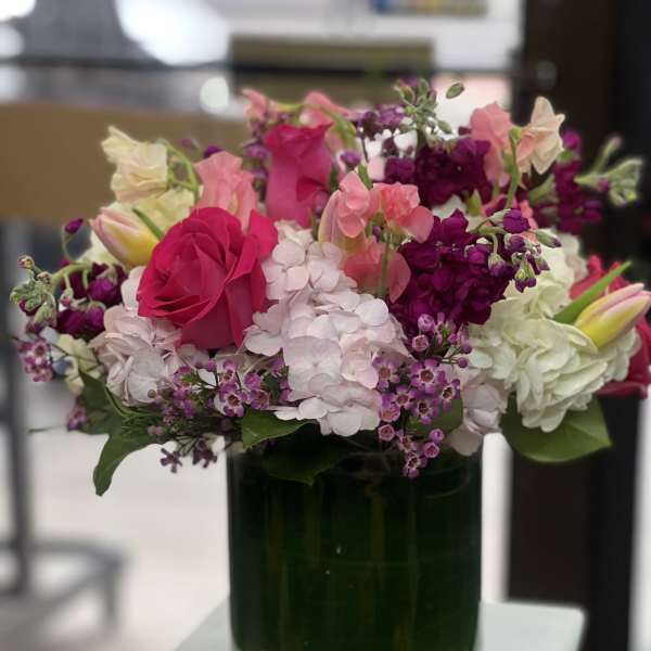 Pink and purple flowers arranged in a green glass vase
