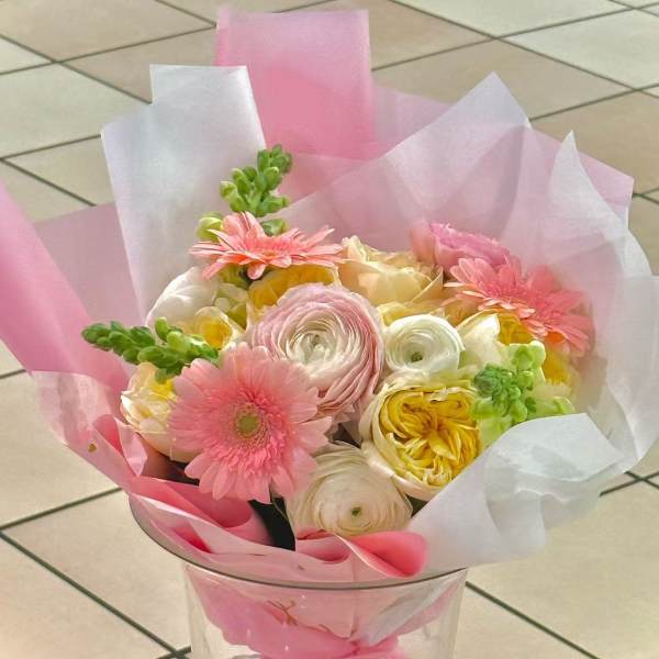 Pink and white bouquet with gerbera daisies and ranunculus in clear wrap
