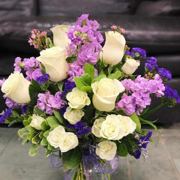 Bouquet of white roses and purple flowers in a glass vase