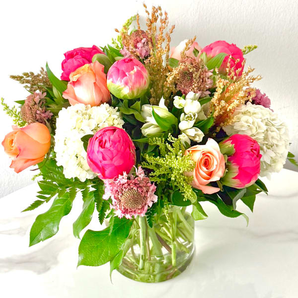 Mixed bouquet of pink and peach flowers in a clear glass vase