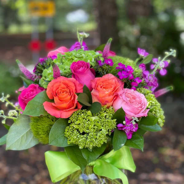 Pink and orange roses in a glass vase with green accents
