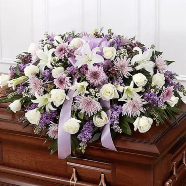 Lavender and white floral casket spray with ribbon accents