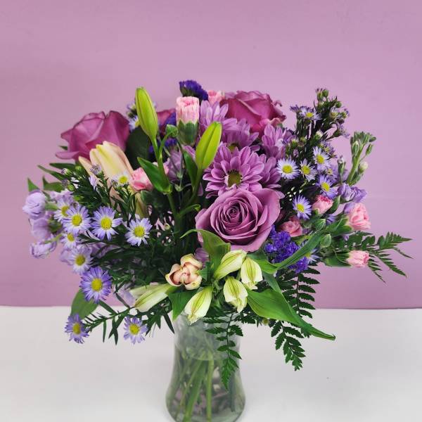 Purple and pink mixed bouquet in a clear glass vase