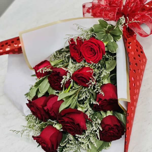 Bouquet of red roses wrapped in white paper with a red ribbon