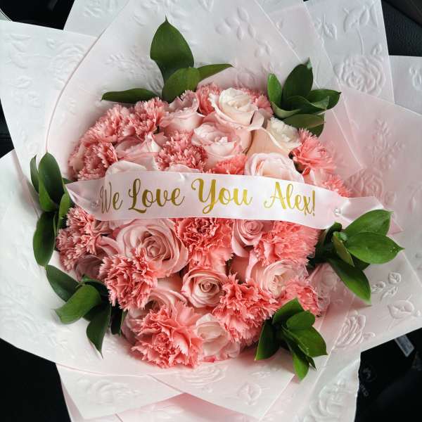 Pink rose and carnation bouquet with a "We Love You Alex!" ribbon